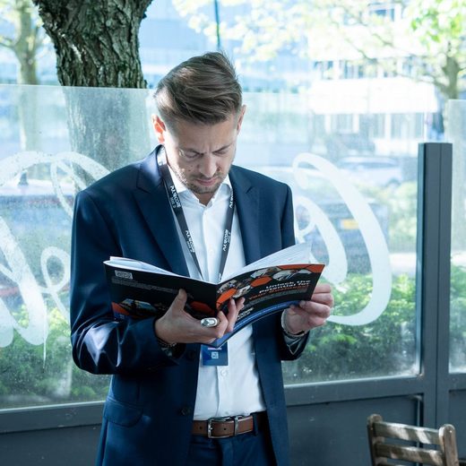 A delegate reading the printed programme beside a window at an Excellence in Digital Banking summit